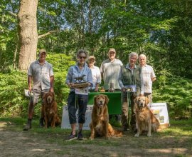 A group of people standing in front of a table with dogs Description automatically generated